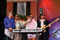 Eine Band mit Instrumenten, Sonnenbrillen und Feder-Boa