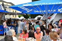 Besucher sitzen vor Ständen mit Getränken und Essen vor dem Staatstheater