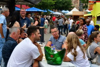 Eine Gruppe Besucher sitzen auf einer Bierzeltgarnitur, im Hintergrund Essenstände in der Obertor- und Türkenstraße