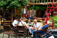 Eine kleine Gruppe sitzt an einem Tisch mit Sofa vor dem Cafe Thonet und unterhält sich angeregt