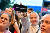 Junge Frau hält ein Mobiltelefon in der Hand auf dem steht "I love you Bri", mit Herz-Emoji