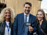 Oberbürgermeister Uwe Conradt steht mit zwei Frauen und hält eine schwarze Schlafmaske „Von hier an blind“ in die Kamera.
