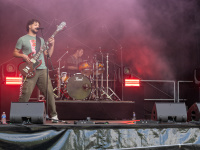 Eine Rockband spielt auf der Rockwiese-Bühne im roten Bühnenlicht vor Publikum.