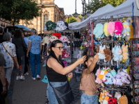 Marktgasse mit Verkaufsständen mit bunten Plüschtieren. Eine Frau und ein Kind betrachten Auslage. Im Hintergrund die Basilika St. Johann. 