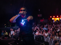  Frontmann von Two Colors mit Sonnenbrille und beleuchtetem Ankersymbol auf der Weste performt direkt vor der Menge. Im Hintergrund feierndes Publikum, rote Lichtakzente und nächtliche Feststimmung.