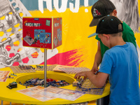 Zwei Kinder spielen an einem gelben runden Tisch mit Experimentierkästen von Kosmos.