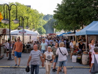 Menschen spazieren entlang von Marktständen und Zelten auf einem gut besuchten Straßenfest.