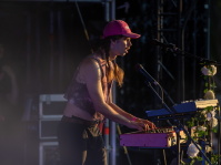 Ein Musiker mit pinkfarbener Kappe spielt konzentriert Keyboard auf der Bühne.