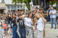 Junge Zuschauer und Performer posieren fröhlich mit Peace-Zeichen vor der Bühne.