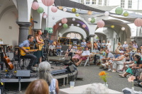 Musikduo mit Gitarren spielt Akustik-Set unter Lampions in historischem Arkadengang.
