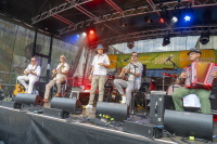 Sechsköpfige Band mit Gitarren und Akkordeon rockt bunt beleuchtete Open-Air-Bühne.