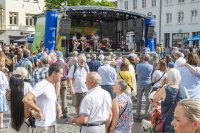 Menschenmenge verfolgt Konzert einer sechsköpfigen Band auf einer Bühne.