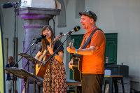 Duo mit Akustikgitarren singt an Mikrofonen vor historischer Säule, SR-Mikrofone deuten auf Radioaufnahme hin.